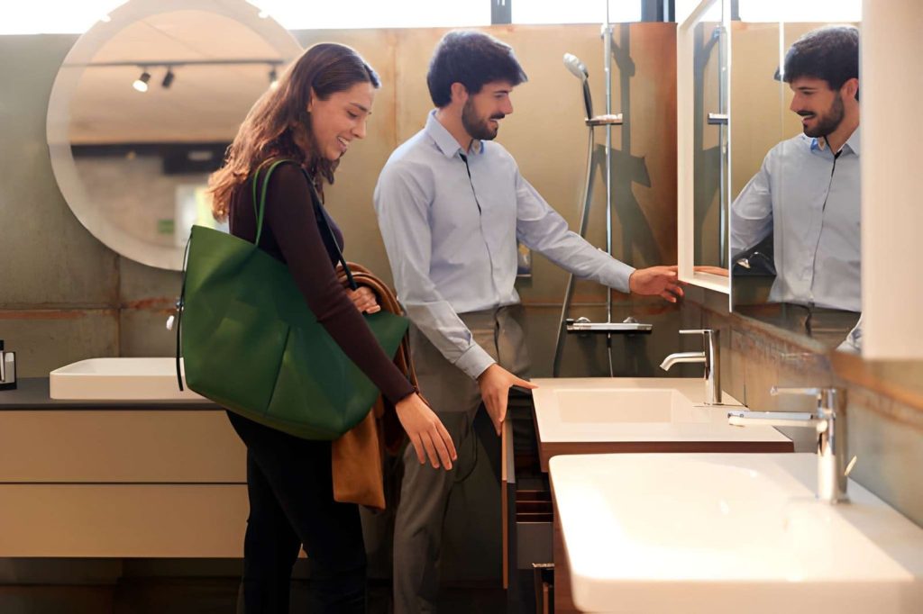 Bathroom remodel companies near me—customer viewing vanity and mirrored cabinet in modern showroom.